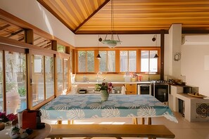 Una cocina moderna con vigas de madera, ventanas amplias y un comedor con mesa.