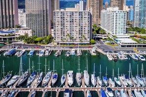 Un port de plaisance où de nombreux bateaux sont amarrés, entouré de grands immeubles et sous un ciel dégagé.