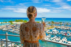 A person holding a glass of white wine, overlooking a marina with numerous boats and a clear blue sky. - Ocean & Marina View Condo, Free Parking, Waikiki (Honolulu)