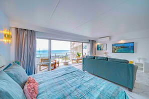 Ein Hotelzimmer mit Balkon, einem Bett, einer Couch und einem Fernseher.