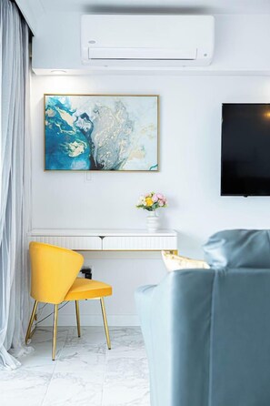 Ein modernes Wohnzimmer mit Fernseher, Schreibtisch mit Stuhl und einer Couch.