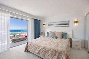 Une chambre avec un grand lit, une vue sur l’océan et un balcon équipé d’un canapé.