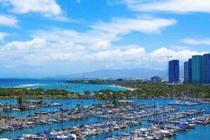 Un puerto deportivo lleno de barcos, una costa y un horizonte urbano con edificios altos.