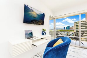 Una sala moderna con un televisor grande, una computadora portátil y una silla azul.