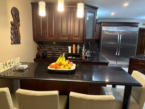 Cocina moderna con armarios de madera oscura, un refrigerador de acero inoxidable y un frutero en la isla.
