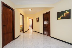A hallway with a tiled floor, wooden doors, and a ceiling light. - Spacious and bright apartment in the heart of Tangier (Tanger)