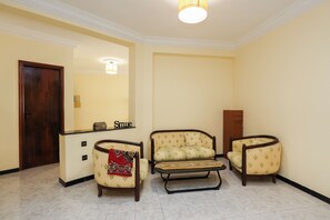 A room with a wooden door, a reception desk, and two armchairs with a patterned cushion. - Spacious and bright apartment in the heart of Tangier (Tanger)