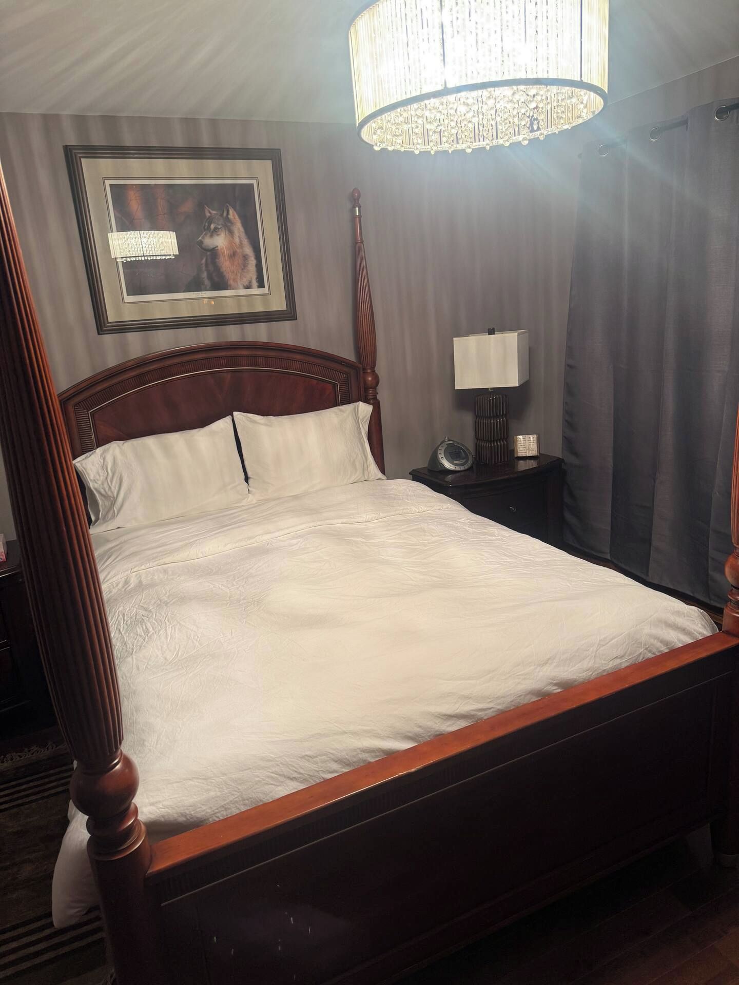 Un lit bien fait, avec une tête de lit en bois, une table de chevet avec une lampe et un tableau encadré accroché au mur.