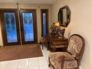 A room with a wooden chair, a small table with a statue, and a mirror on the wall. - Richmond inn room 100 shared bathroom (Thunder Bay)