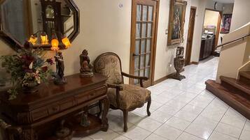 A hallway with a wooden console table, a chair, a large mirror, and a staircase.
