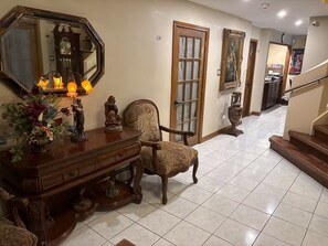 A hallway with a wooden console table, a chair, a large mirror, and a staircase.