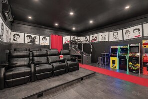 Un cine en casa con un sofá de cuero negro reclinable, una mesita y una alfombra roja.