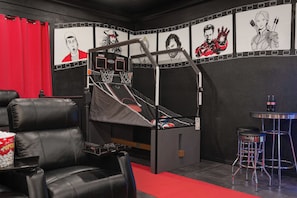 Una habitación con literas, alfombra roja, un cubo de palomitas, un taburete de bar y una pared decorada con arte temático de películas.