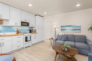 A modern kitchen with white cabinets, a microwave, and a tiled backsplash. - Modern Furnished Santa Barbara Courtyard Retreat with Private Deck & Pool (Santa Barbara)