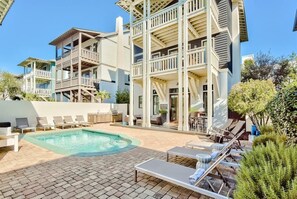 A pool area with lounge chairs and a building with multiple balconies. - Playa Maya (Panama City Beach)