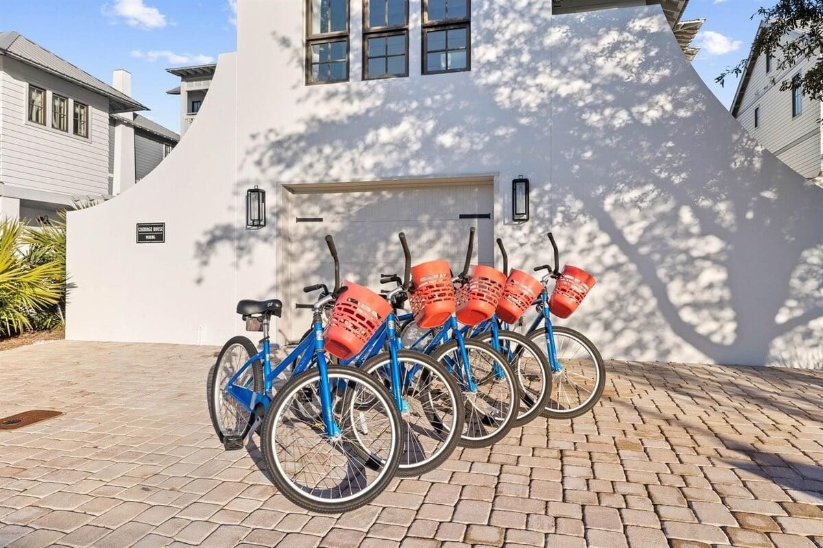 A row of blue bicycles parked in front of a white building with a garage door.