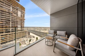 A balcony with a view of a construction site, a sofa, and a small table. - Stayshort - Spacious 2-bedroom Apartment at Skyhills Tower 1 (Dubai)