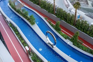 A modern swimming pool with a unique circular water feature, surrounded by a red and grey pathway, and lush greenery. - Stayshort - Spacious 2-bedroom Apartment at Skyhills Tower 1 (Dubai)