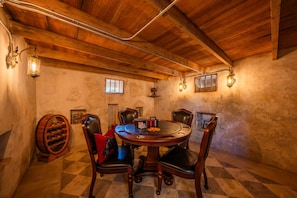 A rustic dining room with a wooden ceiling, a round table, leather chairs, and a wine rack. - Kuenemann Estate - Pool Table & Poker Room (Fredericksburg)