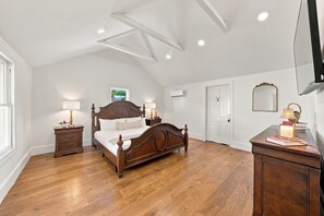 A bedroom with a wooden bed, bedside tables, a dresser, and a ceiling with exposed beams and recessed lighting. - Kuenemann Estate - Pool Table & Poker Room (Fredericksburg)