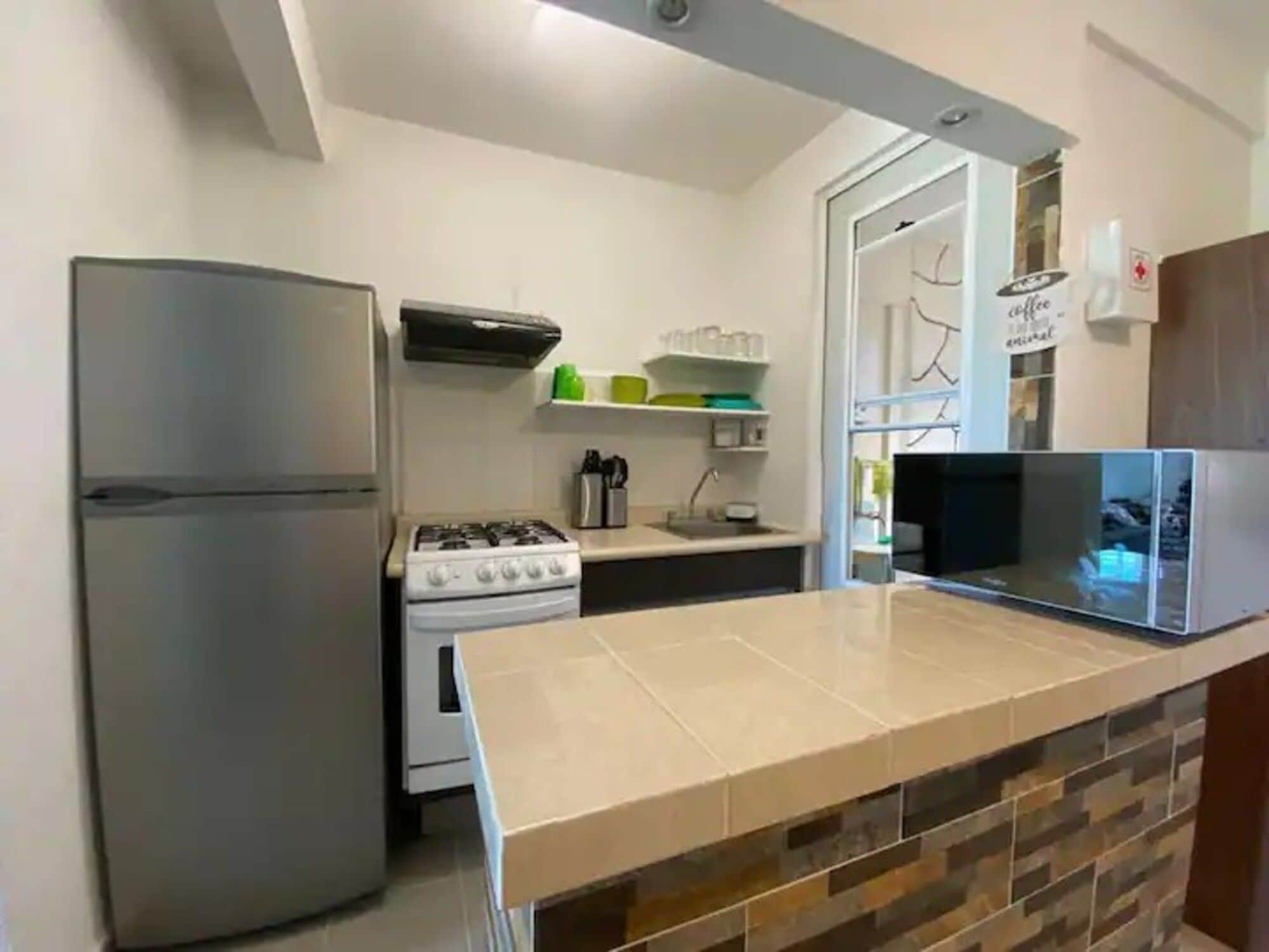 Una cocina equipada con refrigerador, estufa, microondas y salpicadero de azulejos.