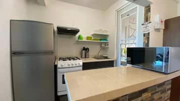 Una cocina equipada con refrigerador, estufa, microondas y salpicadero de azulejos.