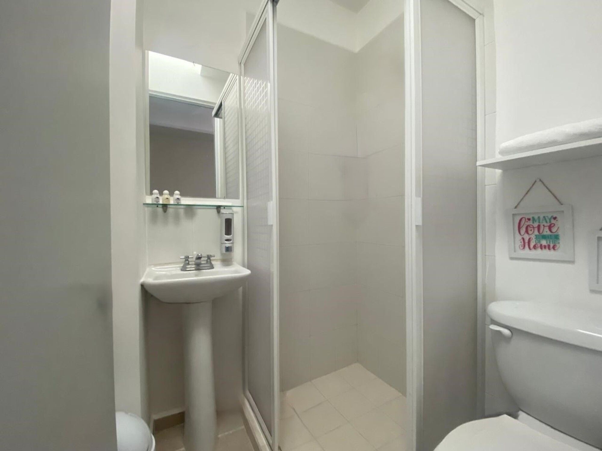 Un baño con lavamanos blanco, inodoro y zona de ducha.