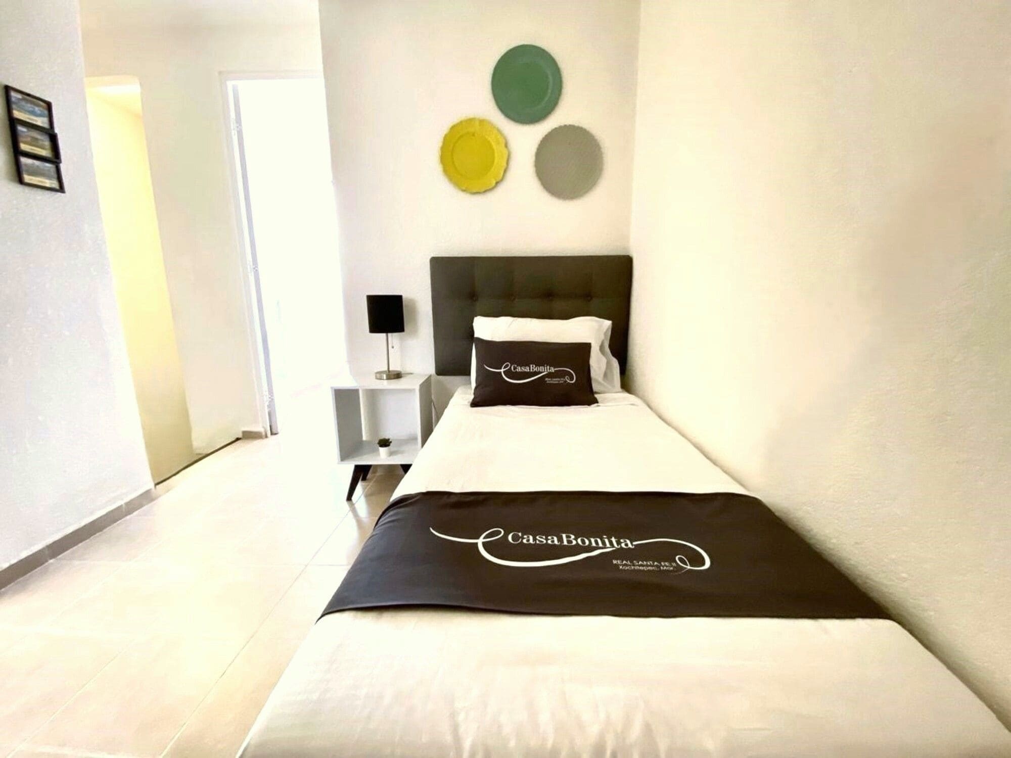 Una habitación de hotel con una cama, una mesita de noche con lámpara y una pared decorada con tres círculos.