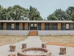 Un motel con un brasero central, un corredor cubierto y una hilera de habitaciones con ventanas y puertas.