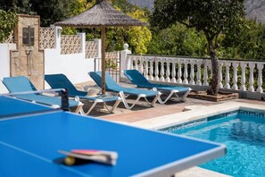 A pool area with lounge chairs and a thatched umbrella. - Villa Nerja | Pool | BBQ | Games | Fireplace (Nerja)