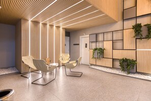 Un área de espera moderna con mostrador de recepción, asientos y una pared decorativa con plantas.