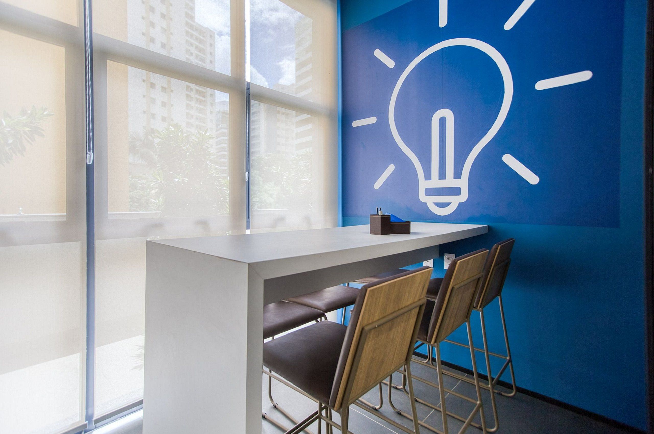 Een moderne kantoorruimte met een bureau, twee stoelen en een muur met een grafische voorstelling van een gloeilamp.
