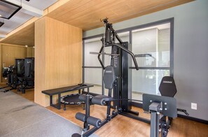 Un gimnasio con una variedad de equipo de ejercicio, incluyendo una jaula de sentadillas y bancos de pesas.
