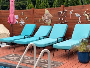 A poolside area with lounge chairs, a pool, and decorative wall art. - Enjoy the pool, relax by the fire pit, or spend time exploring North Georgia! (Oakwood)