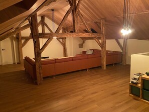 A loft-style room with exposed wooden beams, a red sofa, and a small table. - Detached Holiday Home in La Roche-en-ardenne (La Roche-en-Ardenne)