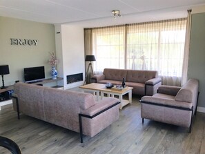 A living room with a sofa, armchairs, a coffee table, a TV, and a fireplace. - Dune Villa With Sauna & Solarium for 8 (Nes)