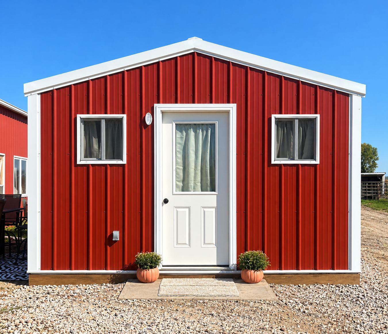Un bâtiment rouge avec une porte blanche, deux fenêtres et des plantes en pot.
