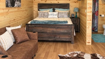 Una habitación acogedora con cama, sofá, piso de madera y alfombra de cuero.