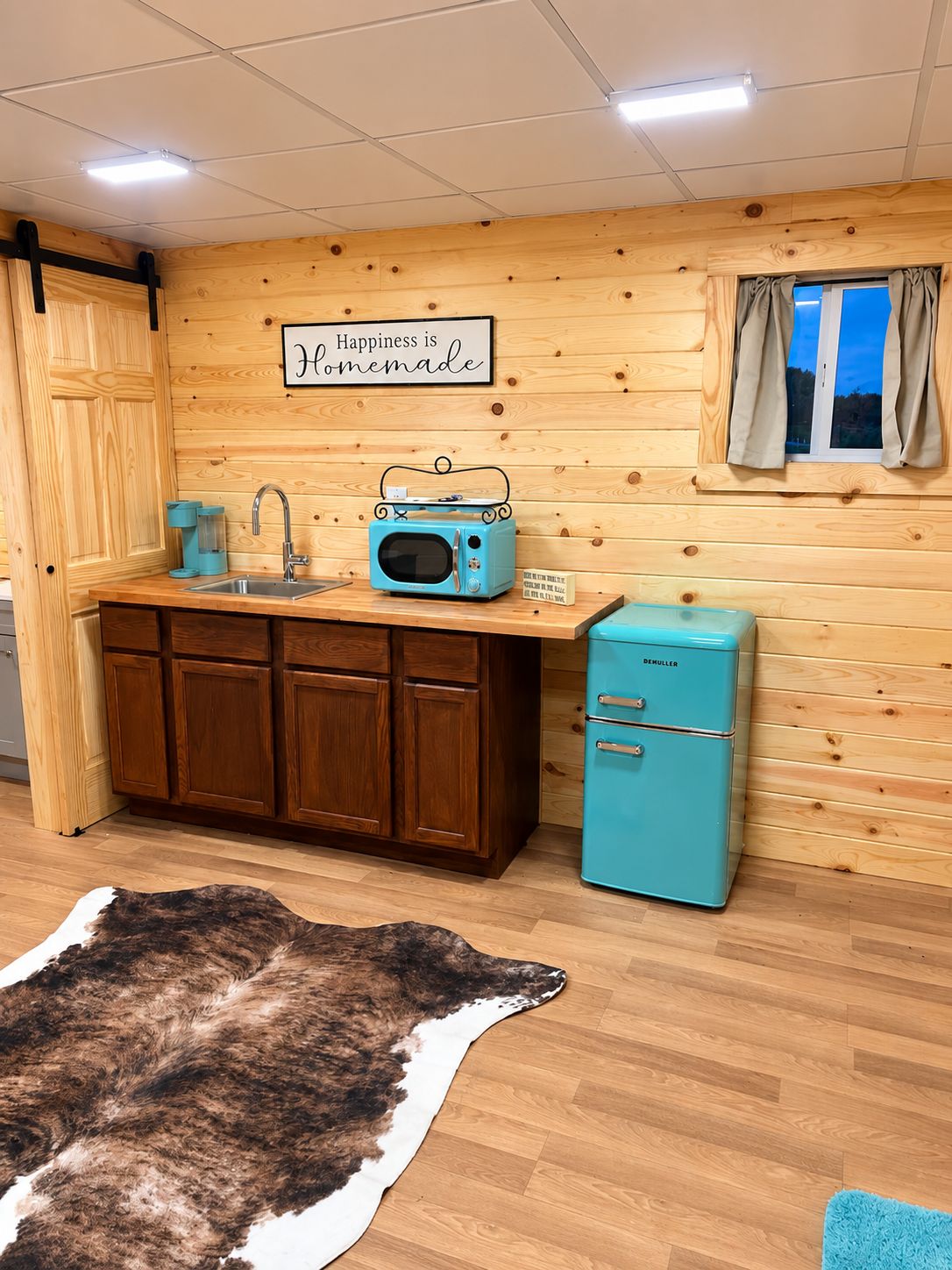 A kitchen with wooden cabinets, a blue refrigerator, a vintage radio, and a sign that says 'Happiness is Homemade.'