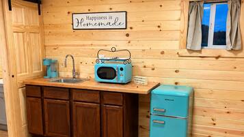 A kitchen with wooden cabinets, a blue refrigerator, a vintage radio, and a sign that says 'Happiness is Homemade.'