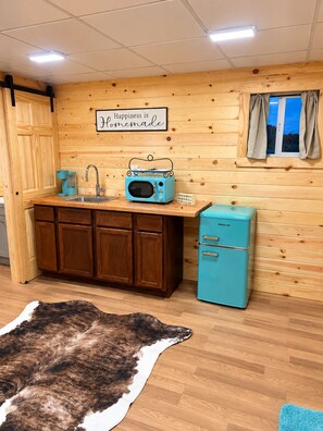 A kitchen with wooden cabinets, a blue refrigerator, a vintage radio, and a sign that says 'Happiness is Homemade.' - Beautiful cabin in Brady perfect for a relaxing getaway (Brady)