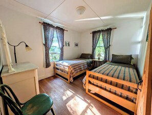 Ein Zimmer mit zwei Betten, einem Schreibtisch, einem Stuhl und einem fenster mit Vorhängen.