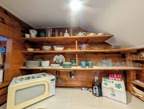 Een keuken met houten planken vol diverse borden en keukengerei.