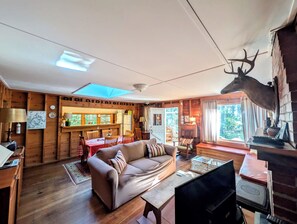 Een gezellig blokhutinterieur met een houten eethoek, een bank en een opgehangen hertenkop.