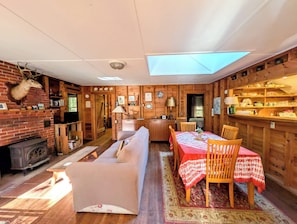 Ein gemütliches Interieur mit Kamin, einem Essbereich mit Tisch und Stühlen sowie einer Holzwand mit Regalen.