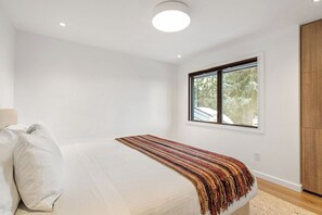 Ein Schlafzimmer mit einem Bett, einem Fenster und einem Holzschrank.