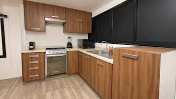 A modern kitchen with wooden cabinets, a built-in oven, a microwave, and a sink.