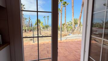 A room with a sliding glass door leading to an outdoor patio with palm trees and a clear sky.