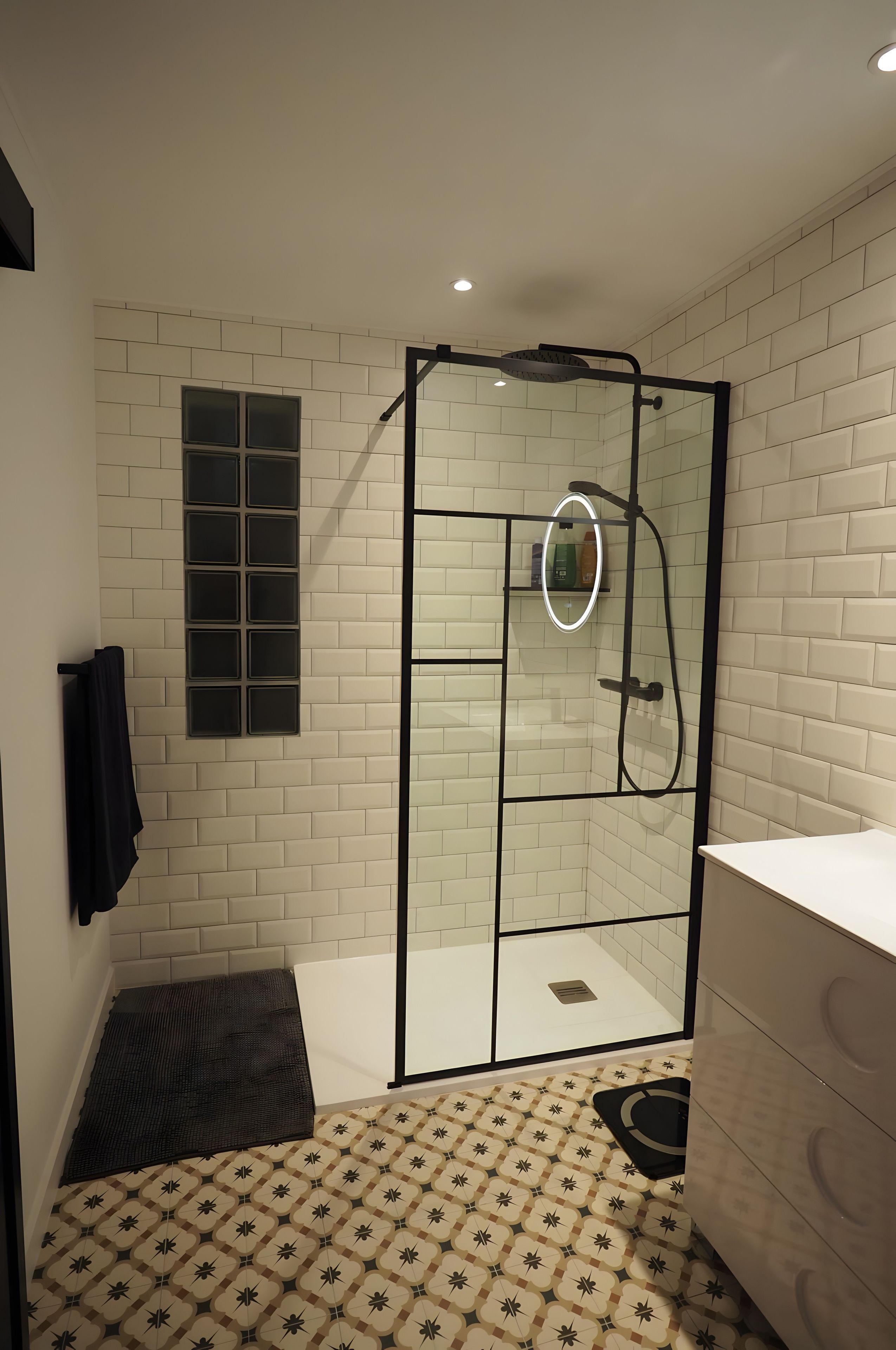 Een moderne badkamer met een douchecabine, een wastafelmeubel en een vloer met een patroon.