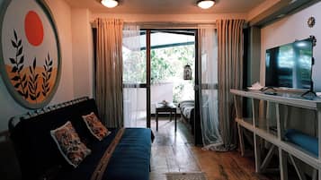 A room with a bed, a television, and a view of greenery outside.